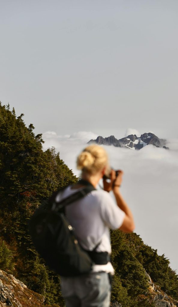 Man taking photo of a mountain from a mountain top.